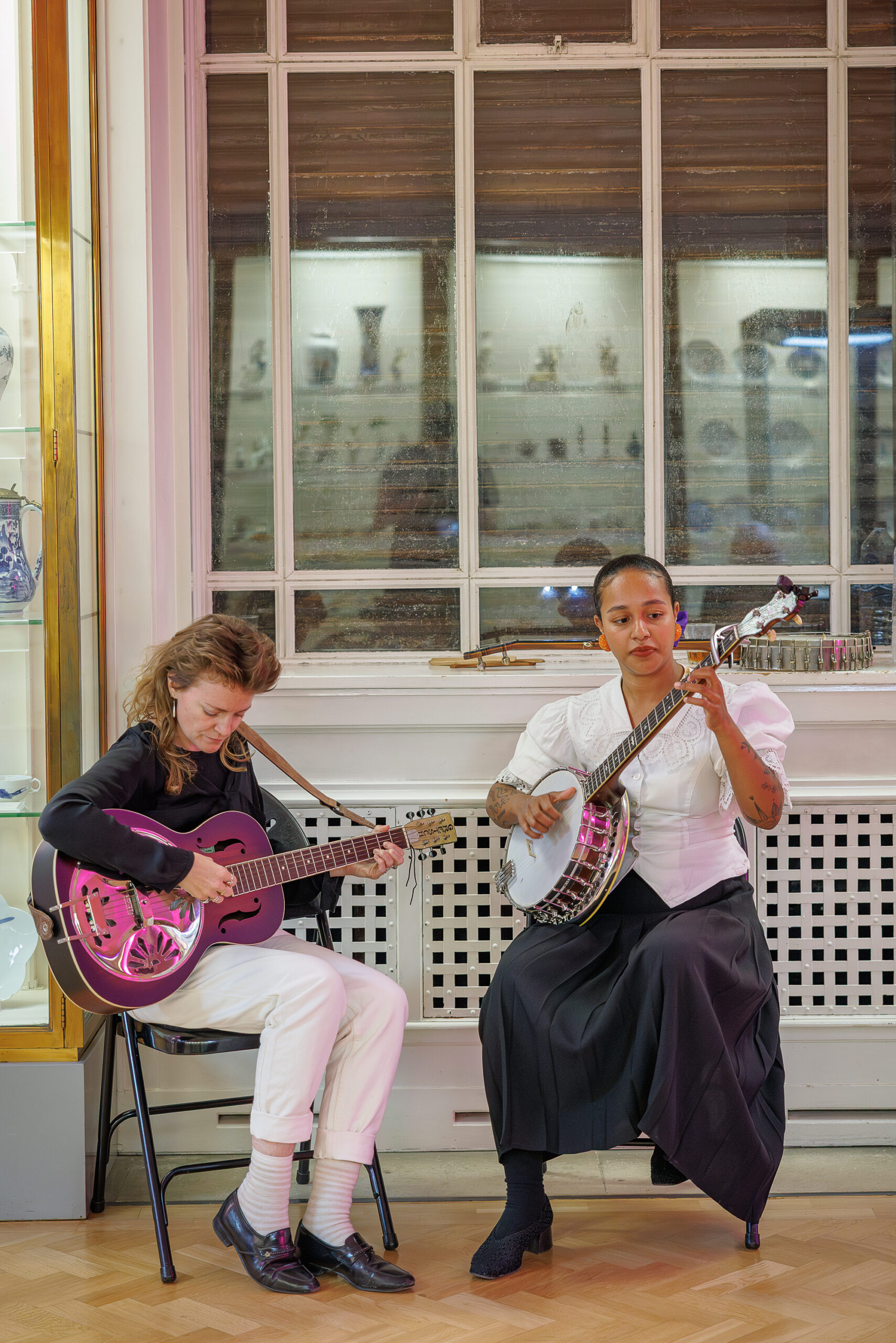 Two female folk musicians perform in a museum gallery