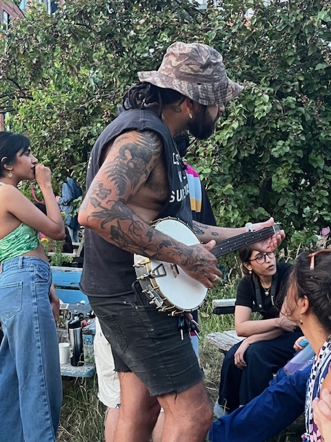 A man of colour playing a banjo at a social gathering in London