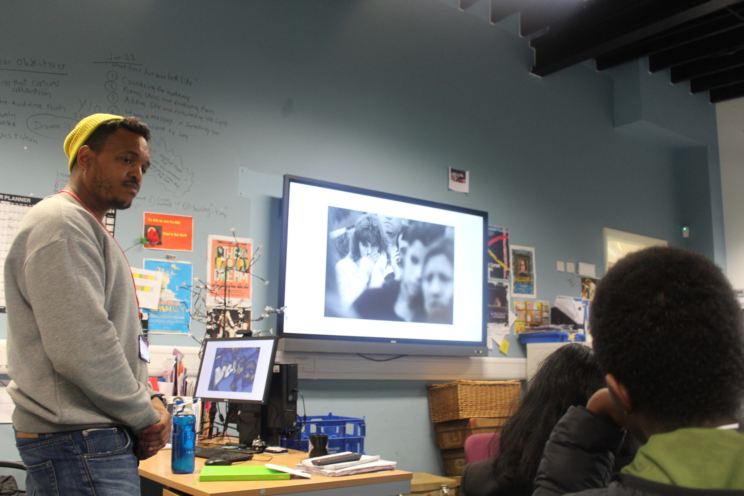 A. man in a classroom showing students a presentation on a screen