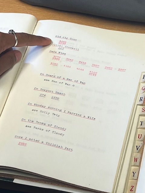 A finger pointing to an entry in a notebook in an archive