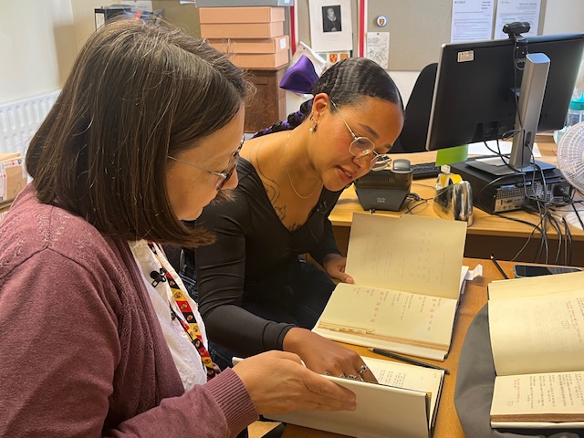 Two people examining notebooks in an archive