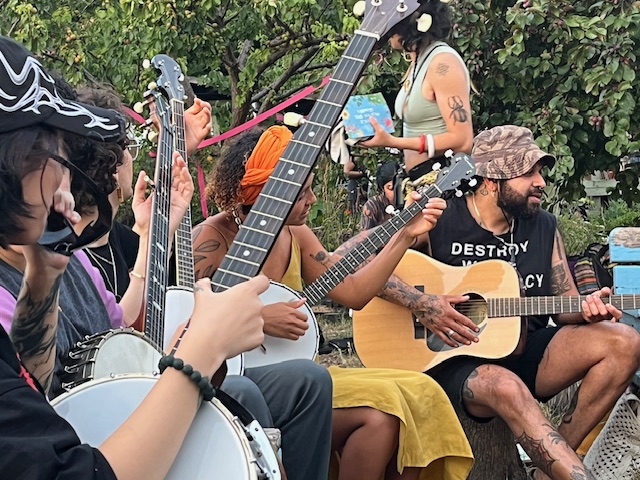 People of colour playing banjo at an outdoor social gathering