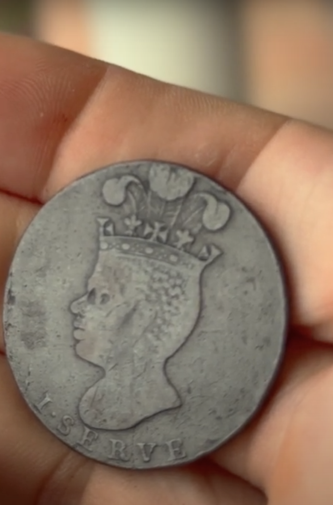 One side of an old Barbados Penny showing the head of a Black man