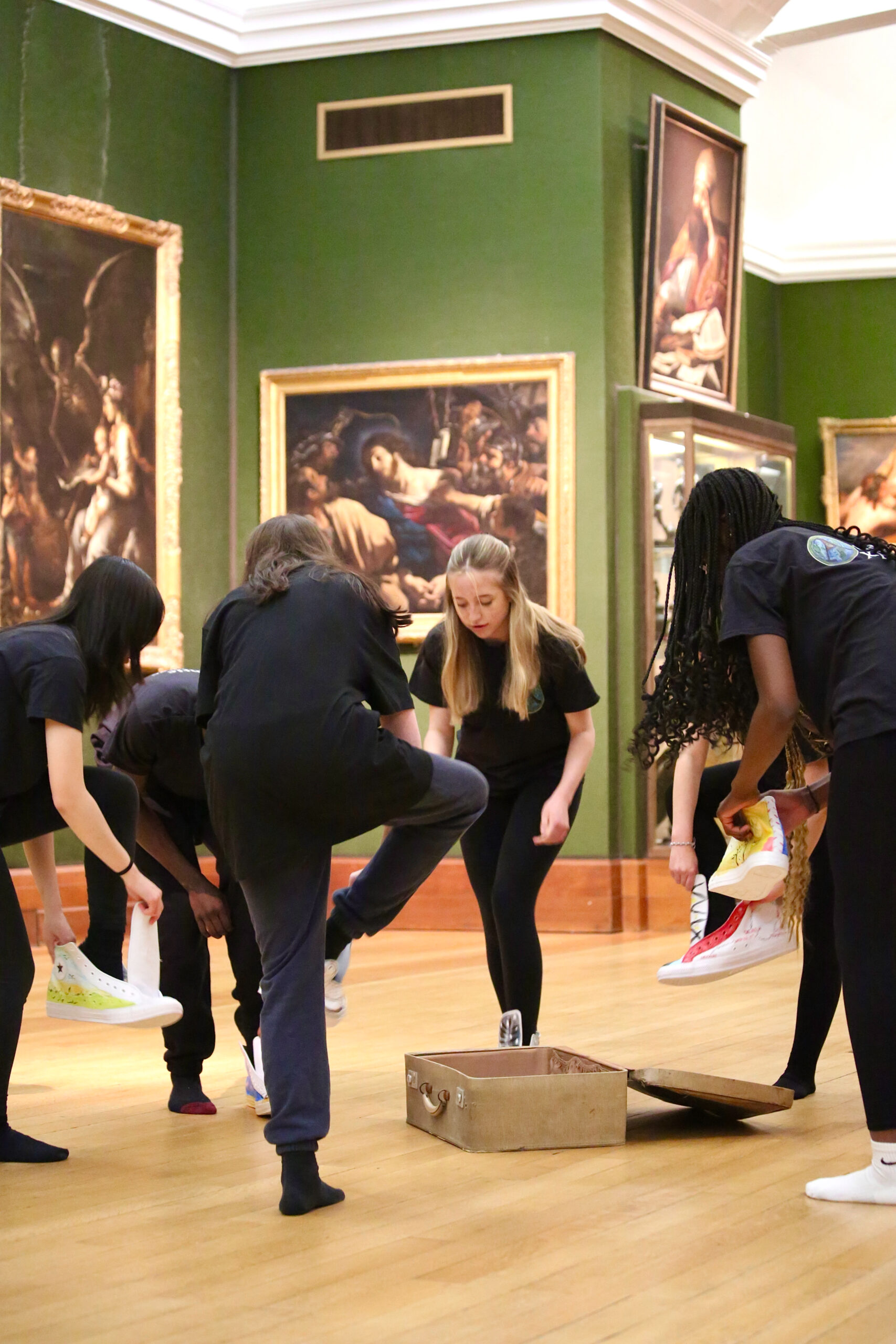 A group of students in a museum gallery performing physical theatre
